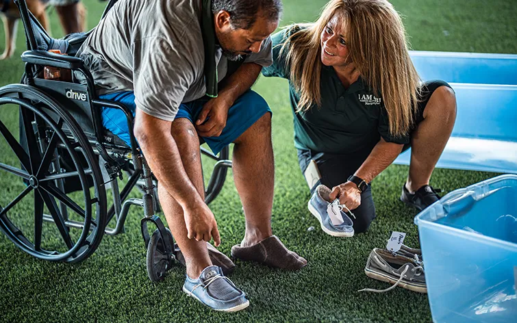 Volunteer helping homeless man in Phoenix with new shoes