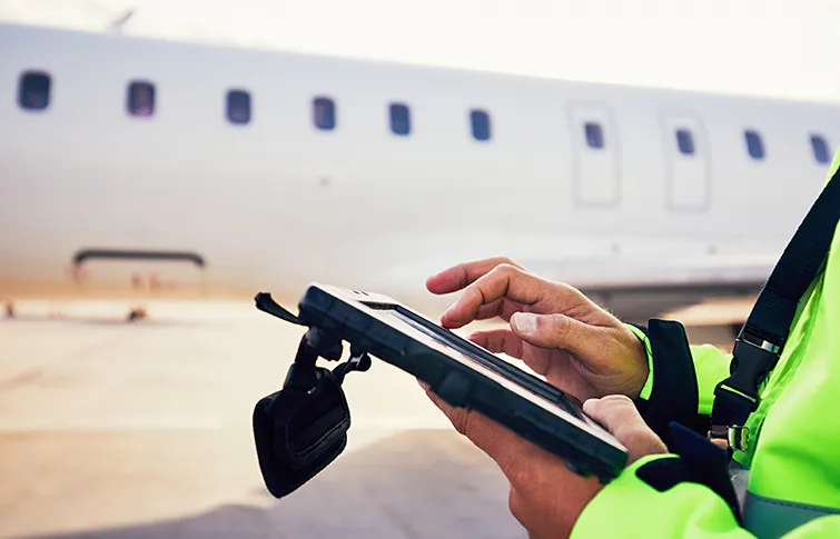 Airport employee with iPad in front of airplane