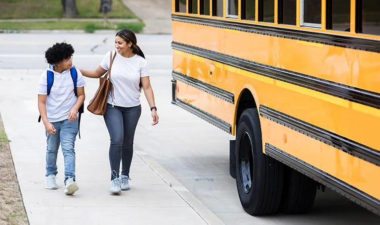 Mom walking preteen to schoolbus