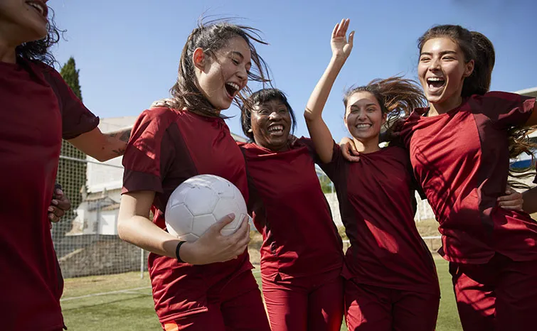 Happy young women playing soccer