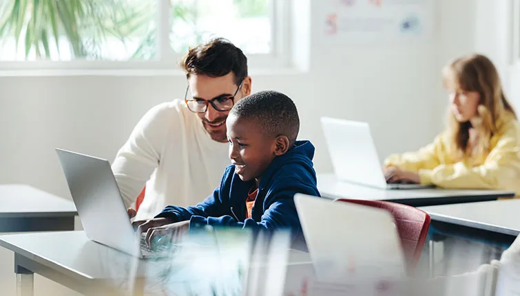 Teacher and student working together at laptop