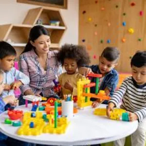 Preschool teacher and students playing with blocks