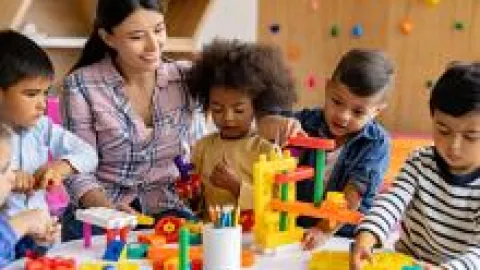 Preschool teacher and students playing with blocks