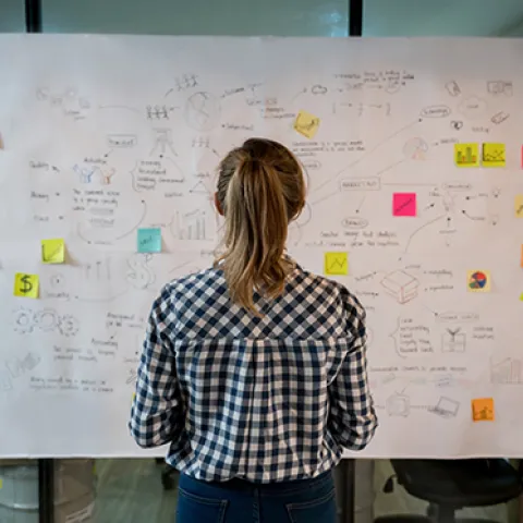 Young worker at strategy board with post-it notes