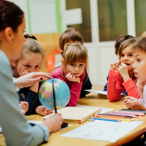 Social studies teacher with a globe and young students