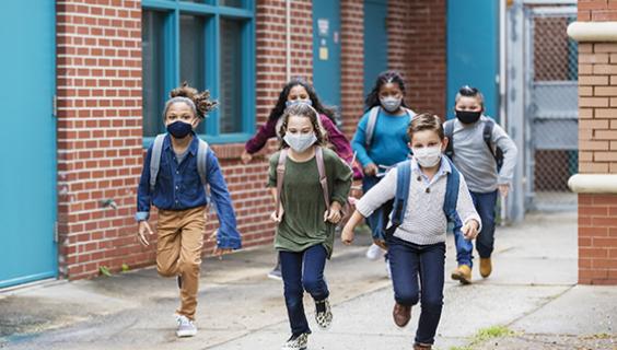Image of kids running outside school, wearing masks