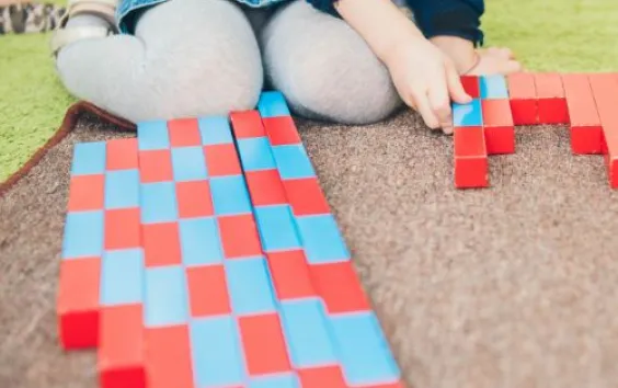 young girl using red and blue blocks to measure 