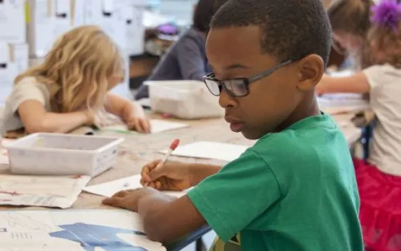 elementary boy writing in book