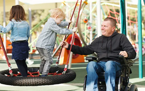 Man in wheelchair at park with kids