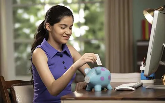 Girl putting money in piggybank