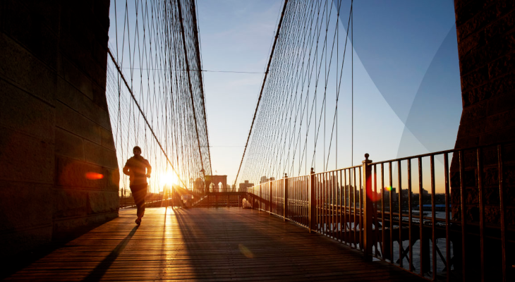 Man running on a bridge at sunrise