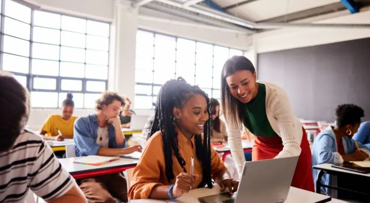 Teacher helping student at desk.