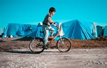 Image of Syrian boy riding a bicycle in a refugee camp 