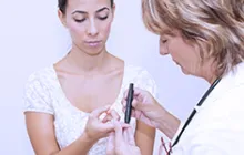 doctor testing young woman's glucose level 