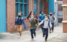 Image of kids running outside school, wearing masks