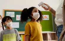 Image of student getting temperature taken by a teacher