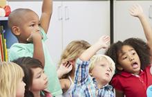 elementary children raising their hands excitedly