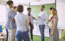Group of teachers and students talking by chalkboard