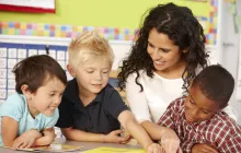 Teacher with happy young students working on a book