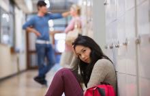 Young woman sitting on floor at locker in school hallway