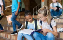 Two girls reading together on school steps