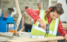 Young woman apprentice using a drill