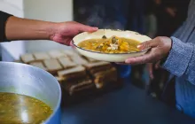 One hand handing another hand a bowl of food