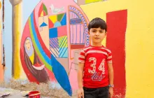 Boy in front of a colorful mural
