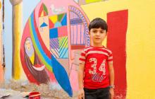 Boy in front of a colorful mural