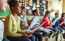 Smiling kids sitting in a row at school