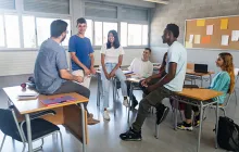 High school students chatting with teacher in classroom
