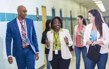 Teachers and administrators walking down school hallway