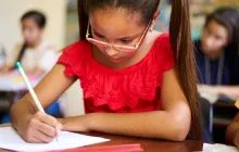 Young female student writing at school desk