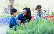 Small children and volunteer working in a garden