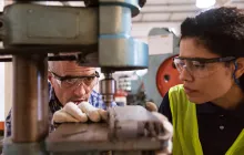Apprentice and mentor with heavy machinery