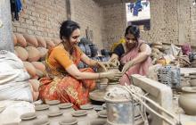 Two Indian women working at a pottery wheel