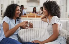 Mentor and mentee sitting on sofa together laughing