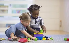 Toddlers playing on the floor with blocks