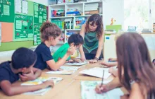 Female teacher working at a table with four elementary students