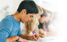 Teenagers sitting in a row doing schoolwork