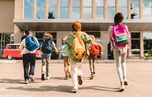 Kids with backpacks running into a school building