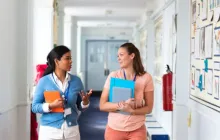 Two teachers walking down hallway and talking
