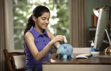 girl putting money in piggybank