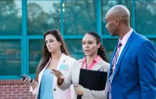three principals talking outside a school