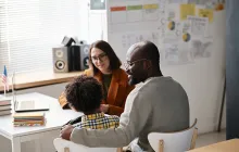 Father and young student talking to teacher in classroom