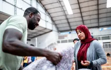 man helping woman in refugee shelter
