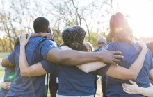rear view of group of volunteers arm-in-arm