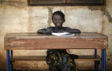 African schoolgirl sitting at desk smiling