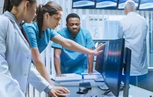 team of healthcare workers looking at computer monitor