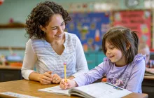 Teacher and young female student working together over a workbook